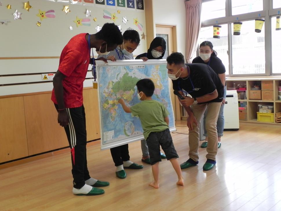 園児と留学生が世界地図を使いながら交流している様子の写真