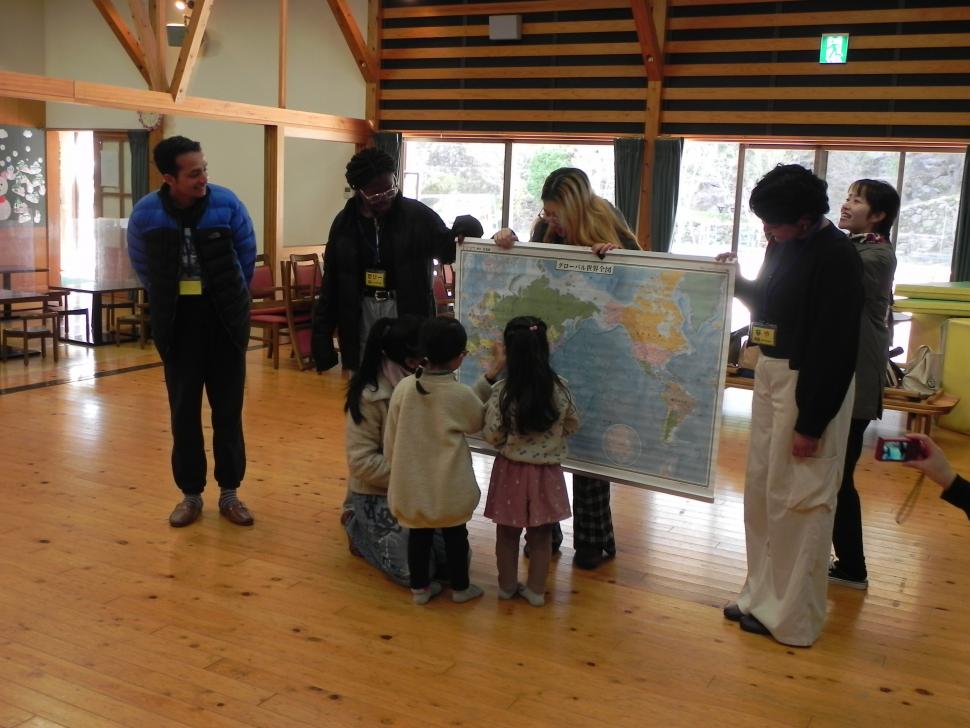世界地図を見ながら留学生と交流をする園児たち
