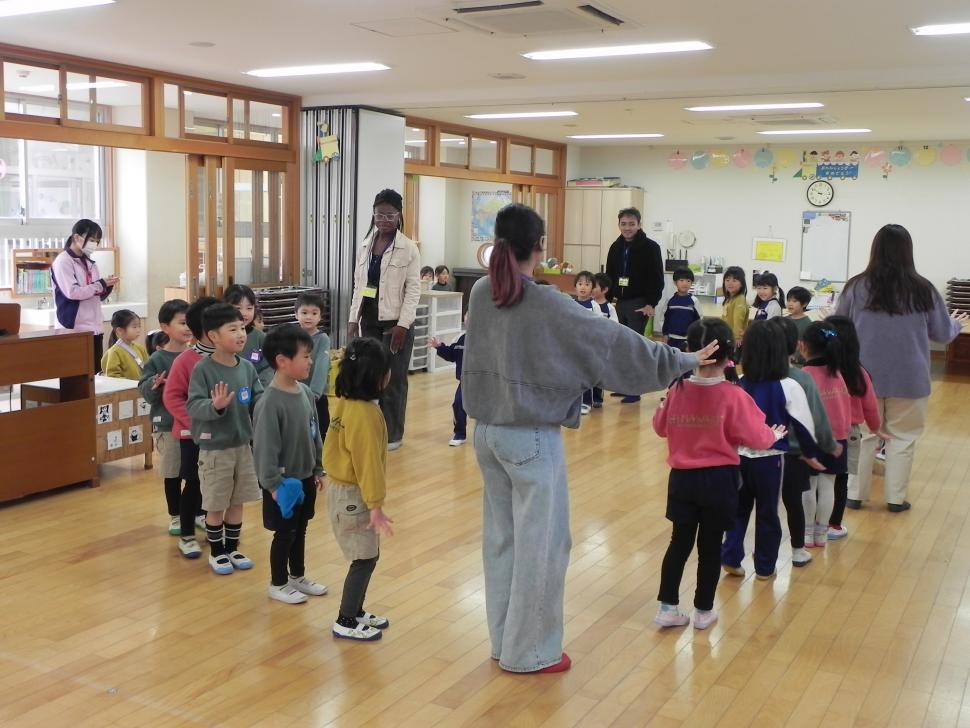 留学生と円になってダンスをする園児たち