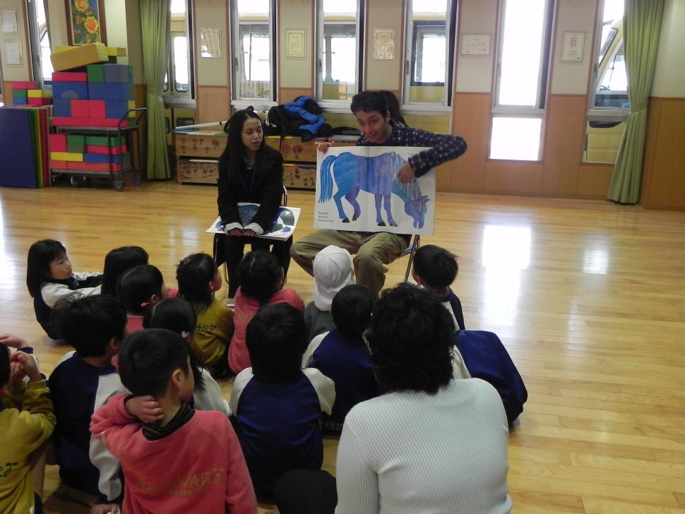 絵本の読み聞かせをする留学生とそれを聞く園児たち