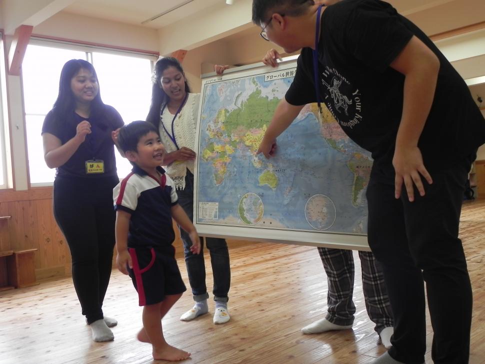留学生と世界地図を見ながら話す園児
