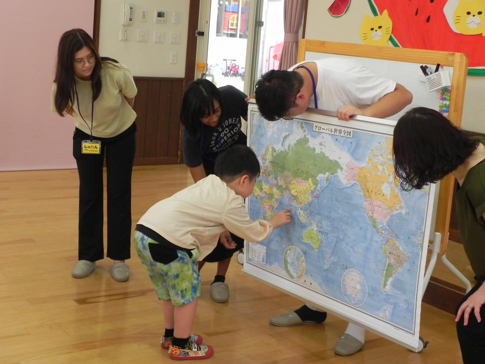 世界地図を見て留学生の母国を探す園児