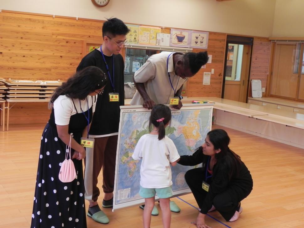 世界地図を見て留学生の母国の場所を探す園児