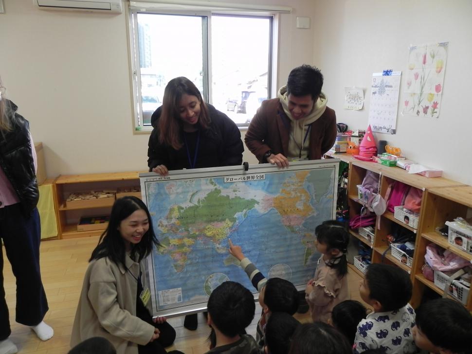 世界地図を見ながら園児たちと留学生が交流