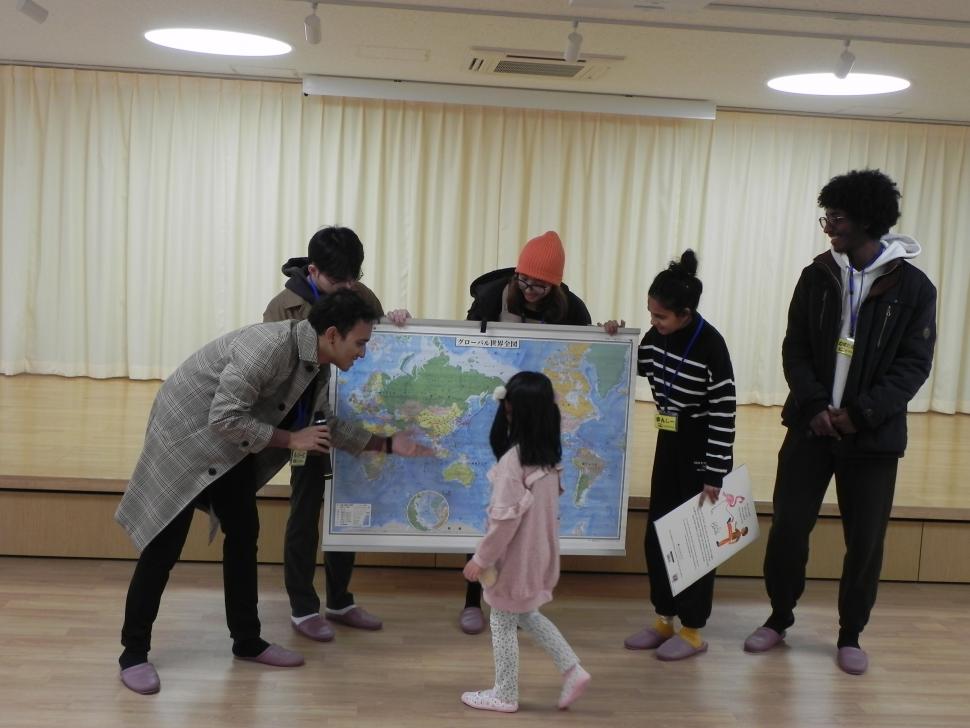 世界地図を見ながら留学生と交流をする園児