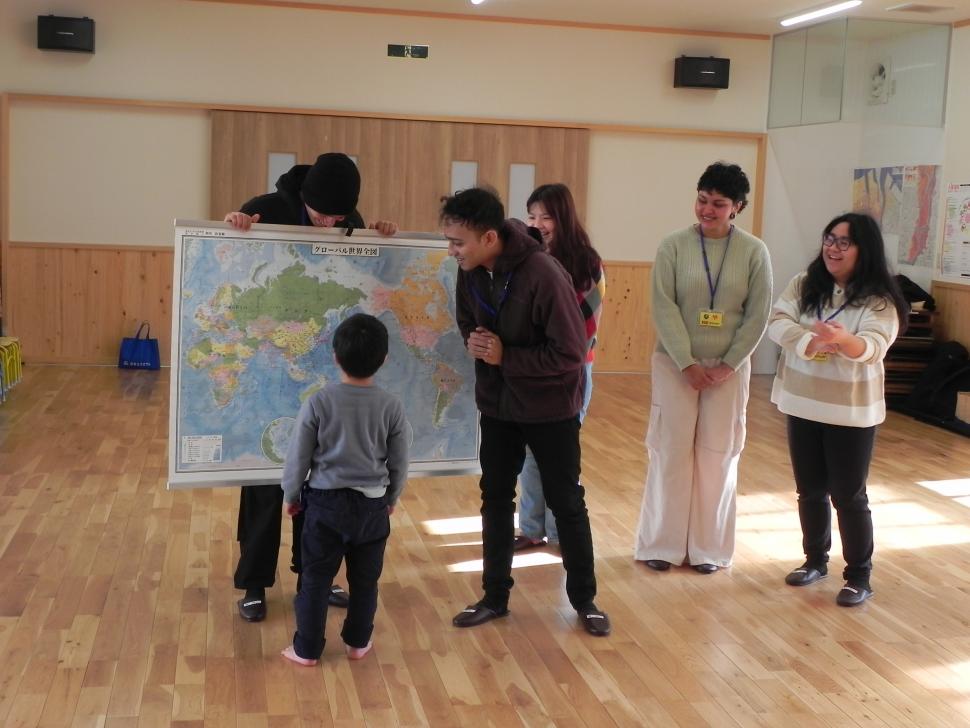 世界地図を見ながら留学生と交流する園児