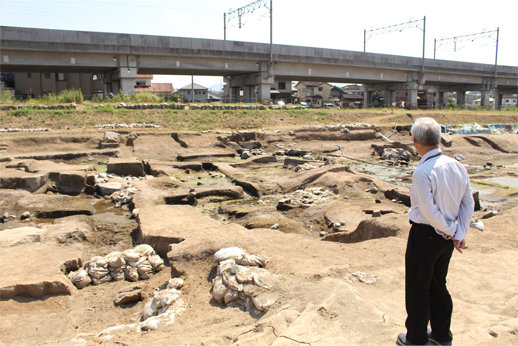 池の遺構を眺める職員の画像